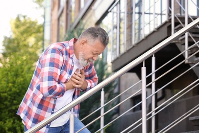 Photo of Mature man having heart attack on stairs, outdoors