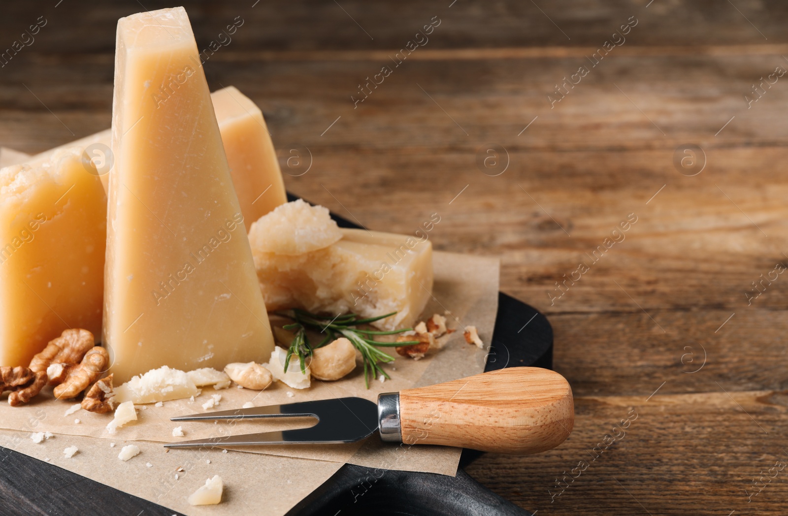 Photo of Delicious parmesan cheese with walnuts and rosemary on wooden table, closeup. Space for text