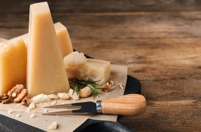 Delicious parmesan cheese with walnuts and rosemary on wooden table, closeup. Space for text