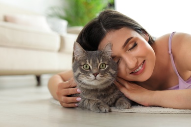 Photo of Young woman with cute cat at home, space for text. Pet and owner