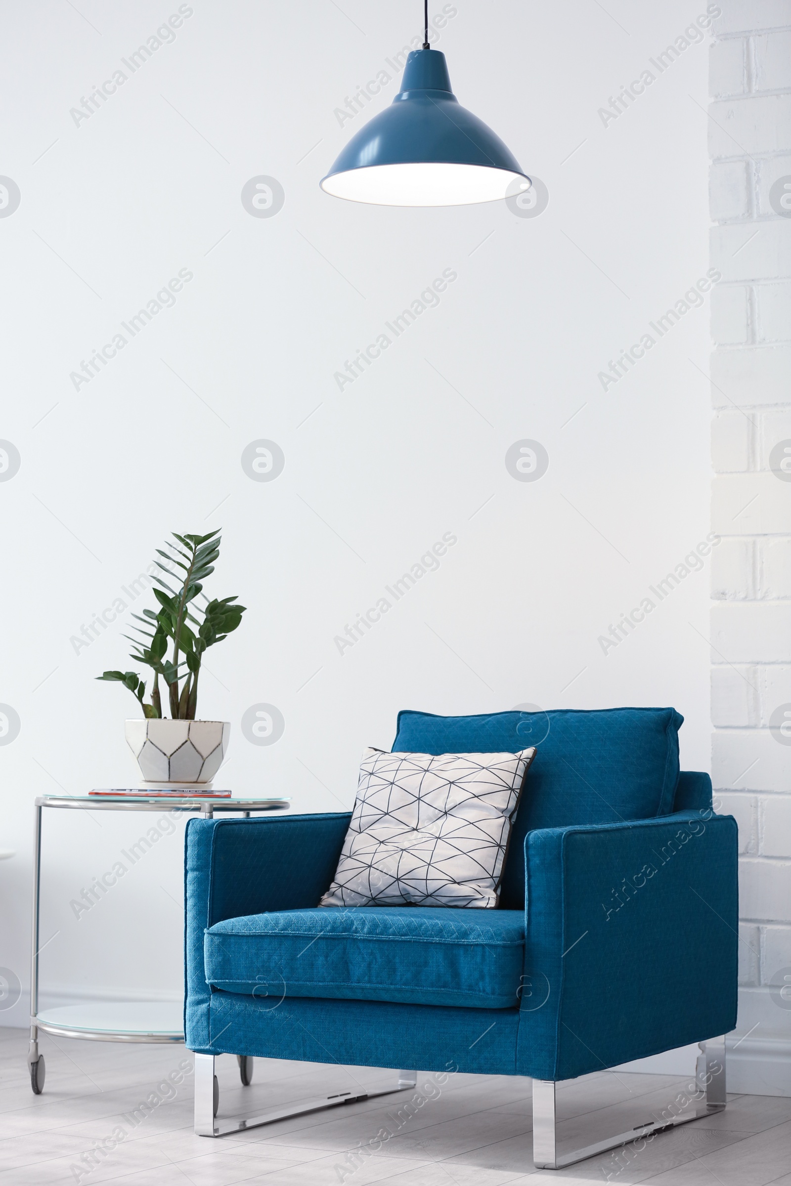 Photo of Modern lamp with plant on table and armchair indoors