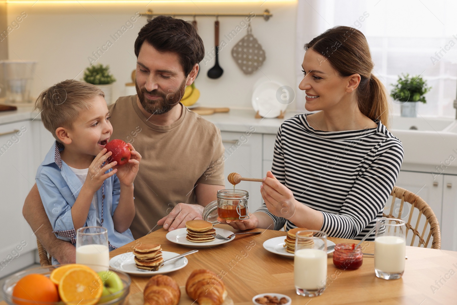 Photo of Happy family having breakfast at table in kitchen