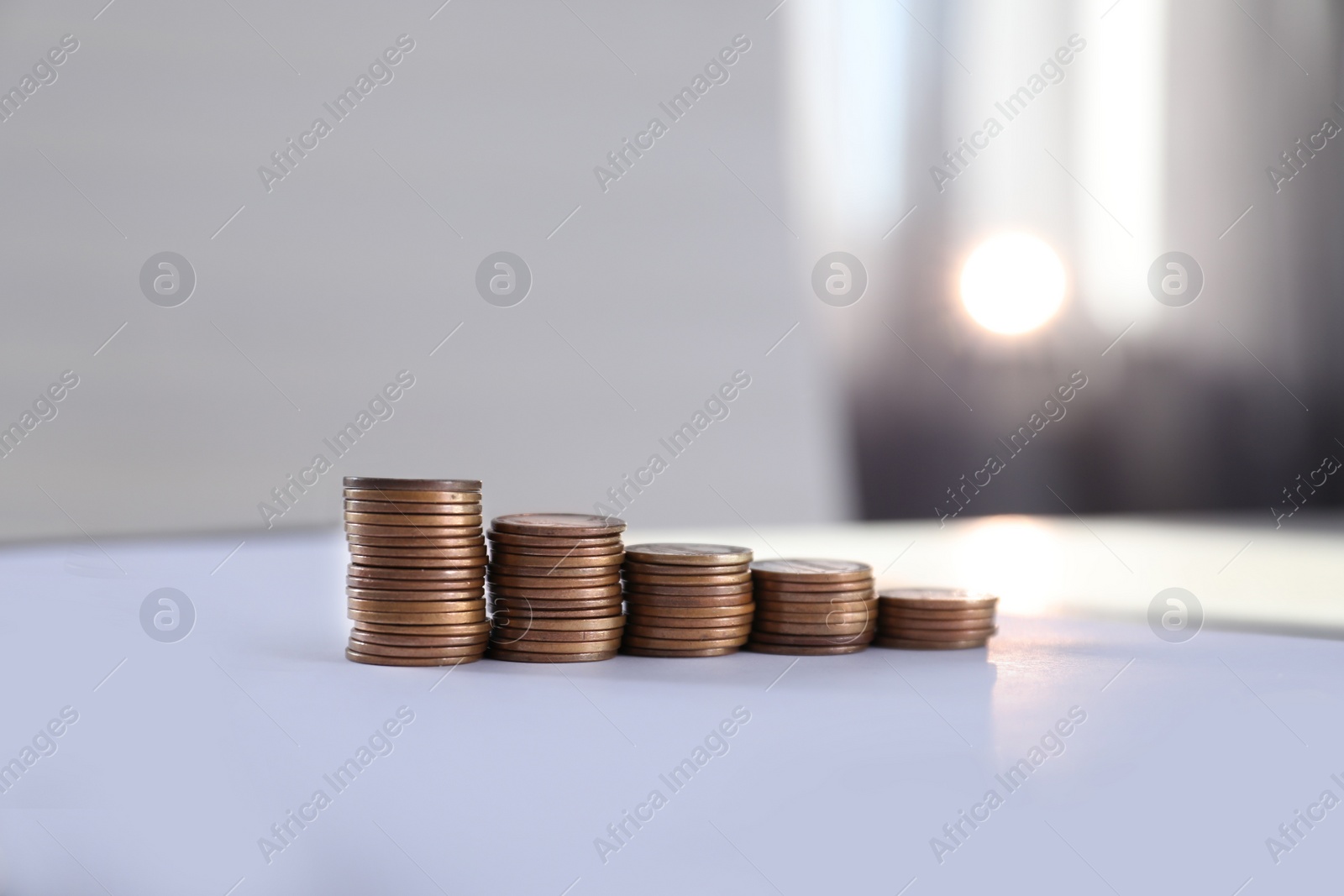 Photo of Stacks of coins on table against blurred background