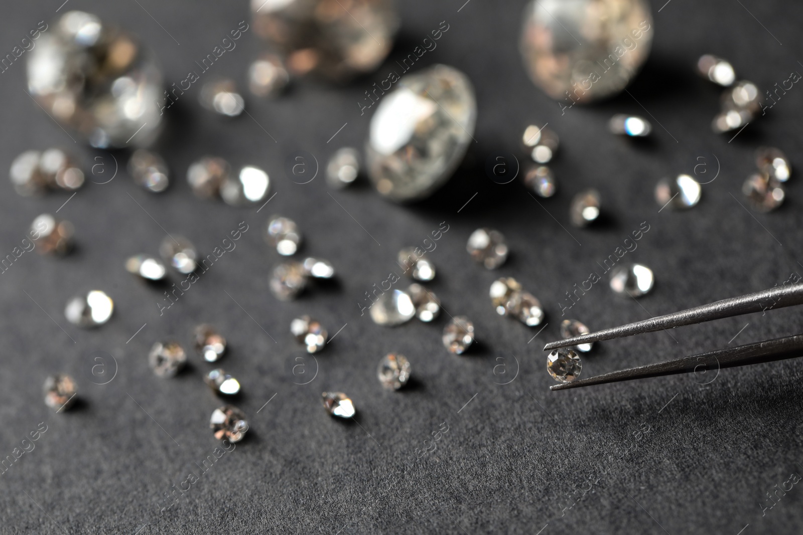 Photo of Tweezers with beautiful gemstone over grey table