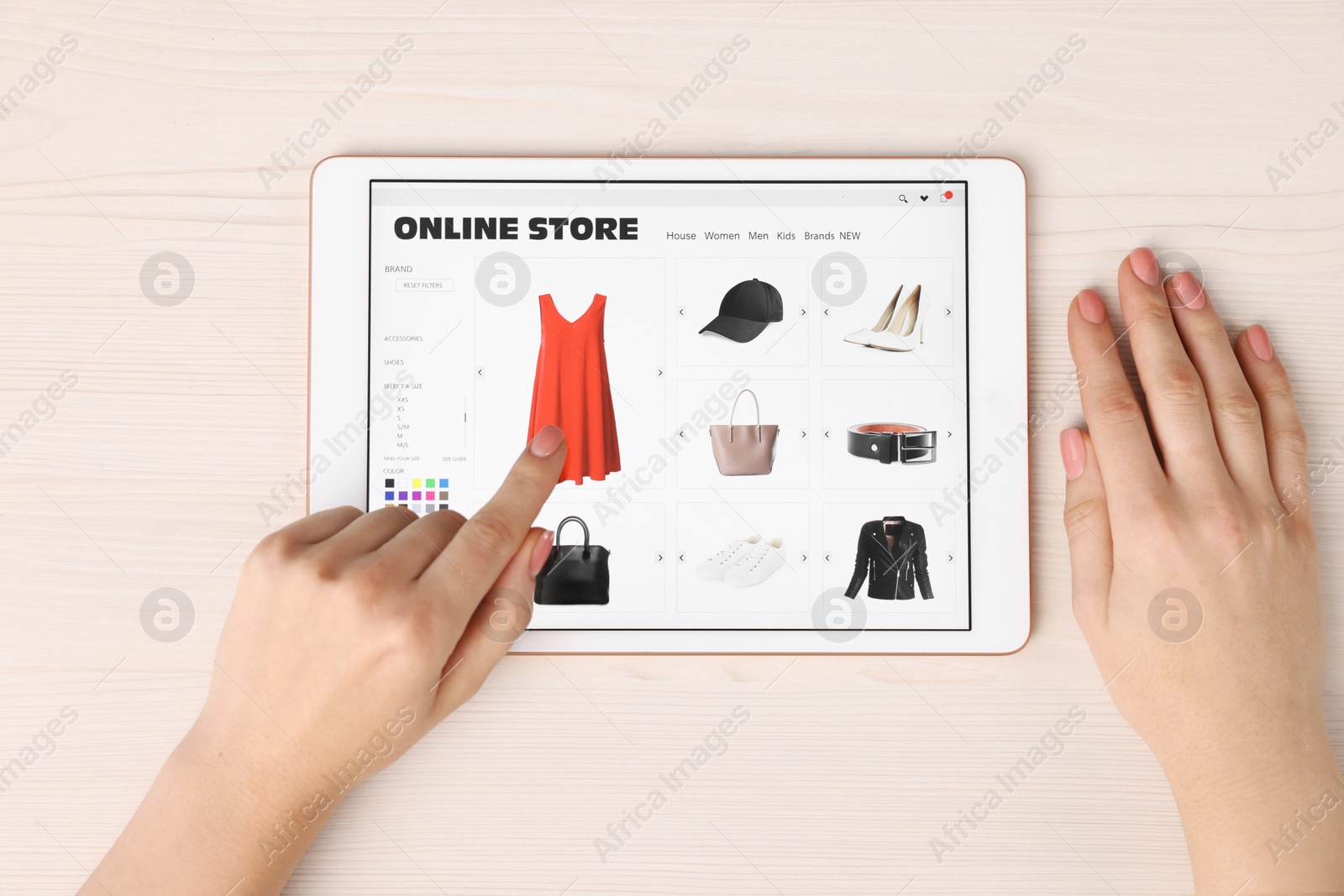 Photo of Woman with tablet shopping online at white wooden table, top view