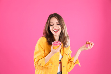 Beautiful young woman with donuts on pink background