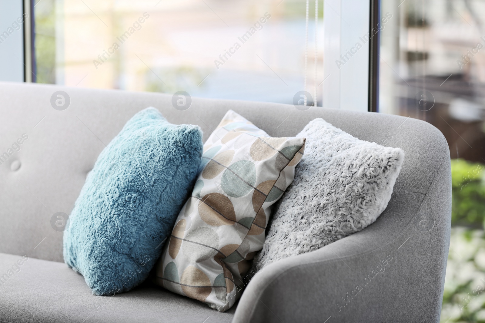 Photo of Different soft pillows on sofa in room. Interior element