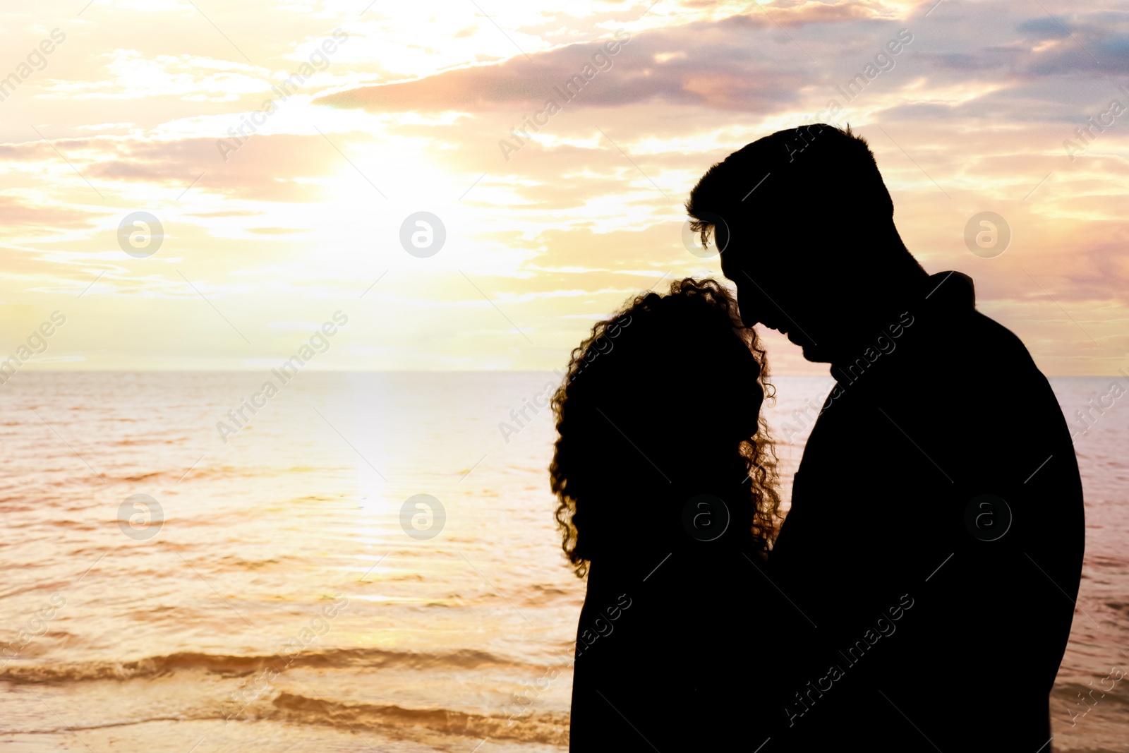 Image of Silhouette of lovely couple spending time together near sea at sunset