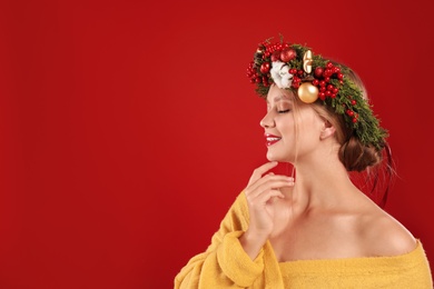 Photo of Beautiful young woman wearing Christmas wreath on red background. Space for text