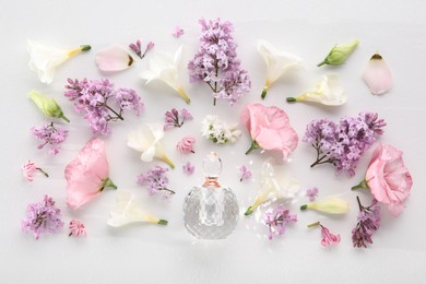 Luxury perfume and floral decor on white background, flat lay