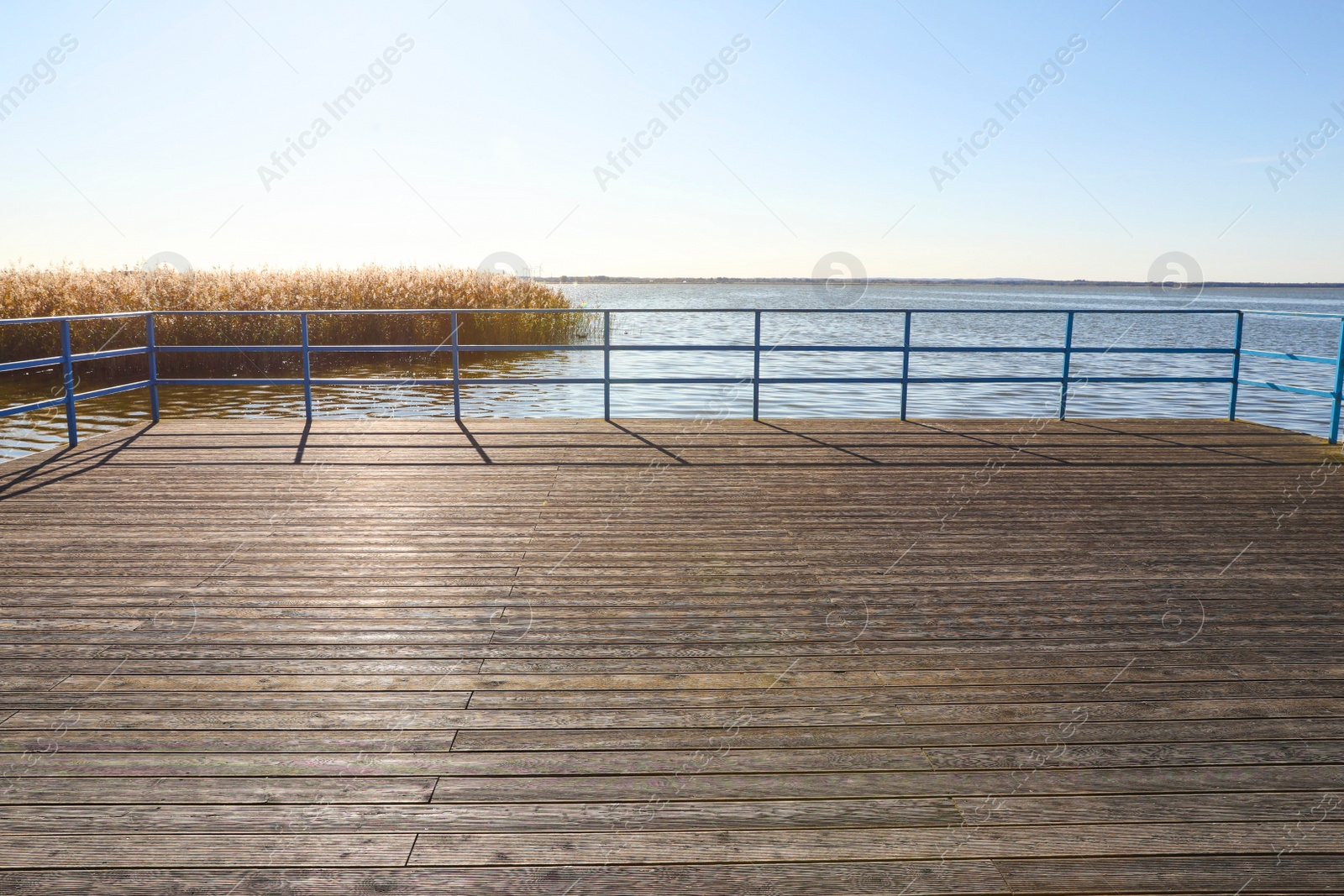 Photo of Beautiful view of wooden terrace with railing near river on sunny day