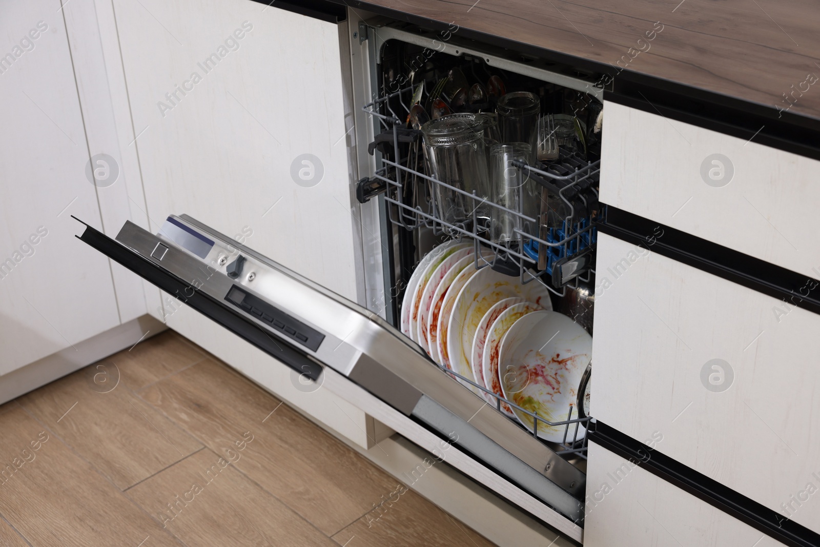 Photo of Open modern dishwasher with dirty tableware in kitchen