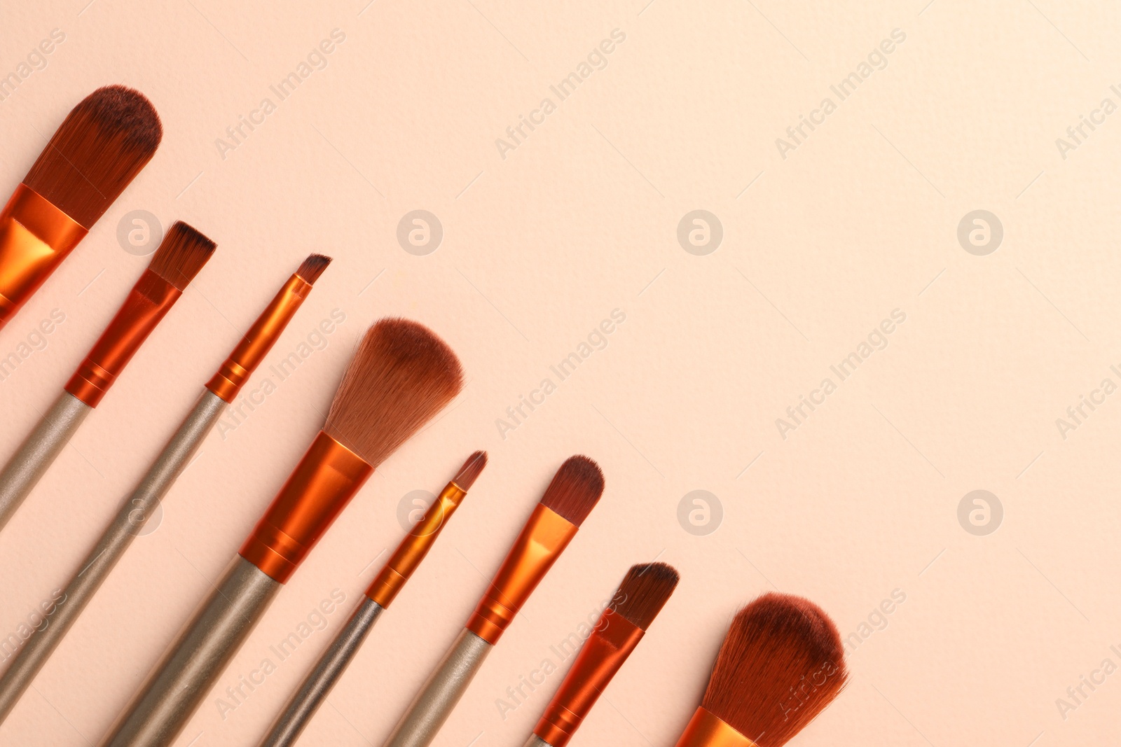 Photo of Set of makeup brushes on beige background, flat lay. Space for text