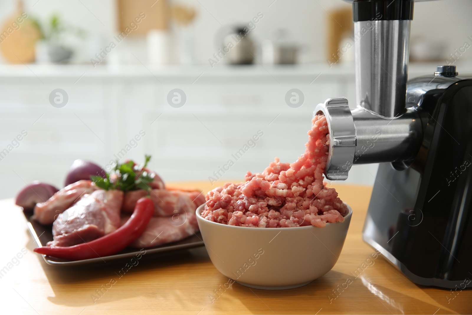 Photo of Modern meat grinder and products on wooden table in kitchen