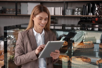 Photo of Happy business owner with tablet in bakery shop