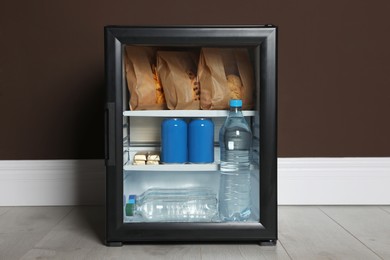 Photo of Mini bar filled with food and drinks near brown wall indoors