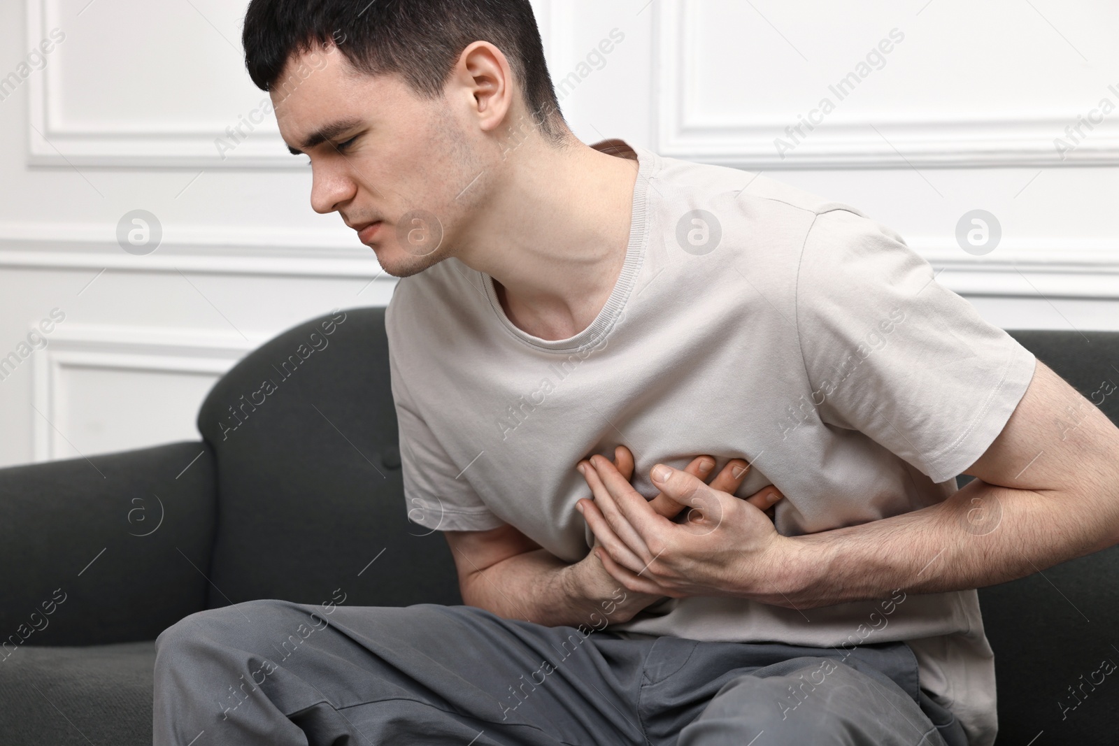 Photo of Young man suffering from heart hurt on sofa at home