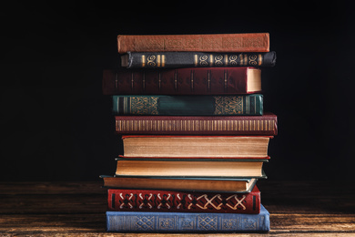 Collection of different books on wooden table against dark background