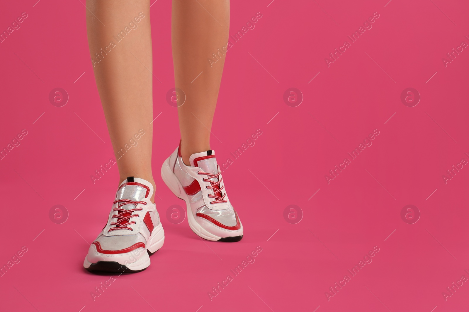 Photo of Woman wearing sneakers on pink background, closeup. Space for text