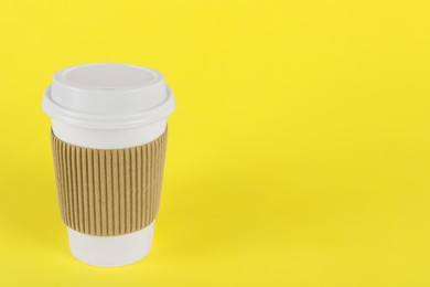 Paper cup with plastic lid on yellow background, space for text. Coffee to go
