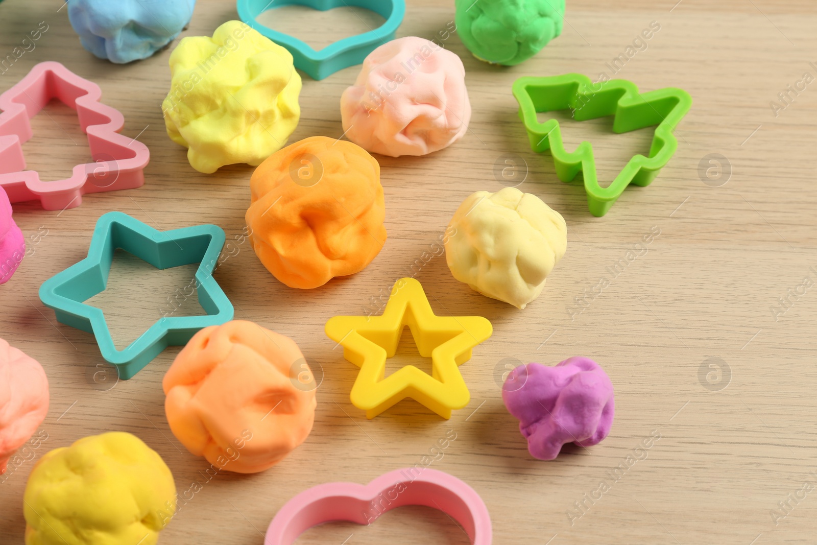 Photo of Different color play dough with molds on wooden table