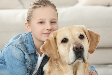 Cute child with her Labrador Retriever indoors. Adorable pet