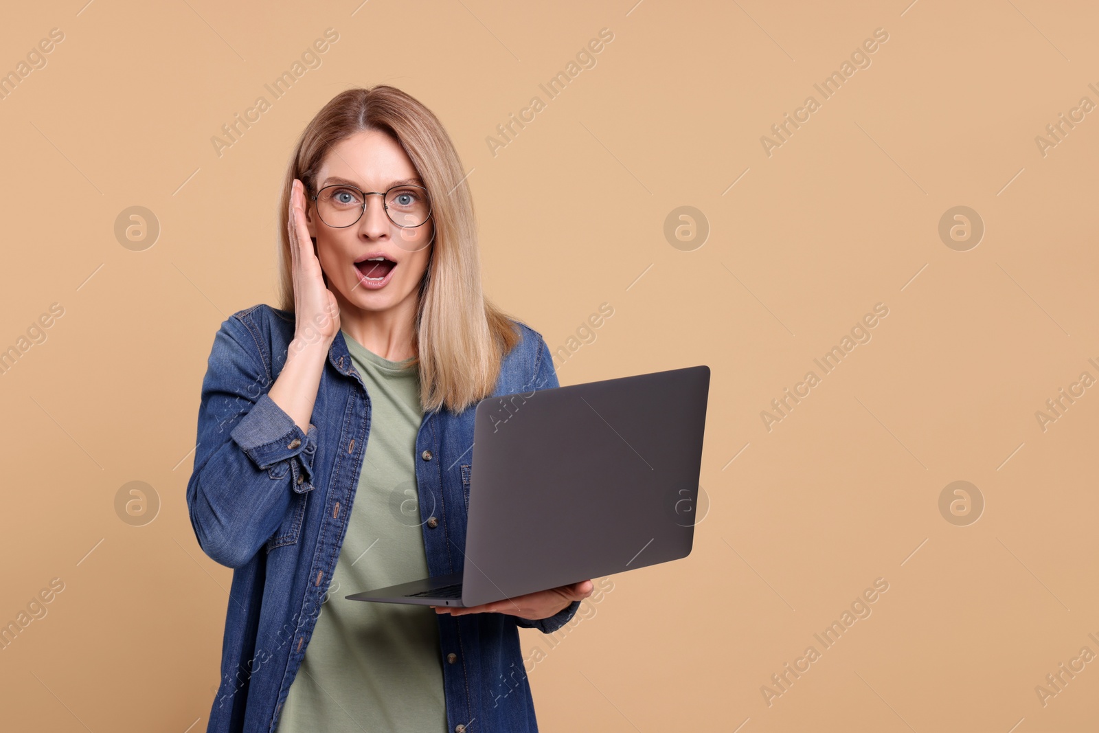 Photo of Emotional woman with laptop on beige background. Space for text