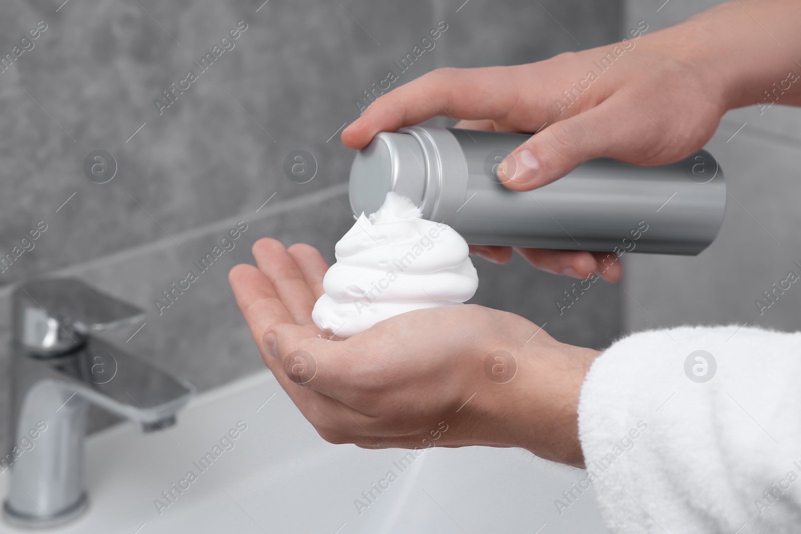 Photo of Man applying shaving foam onto hand in bathroom, closeup