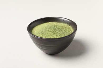 Photo of Wheat grass powder in bowl on light table, closeup