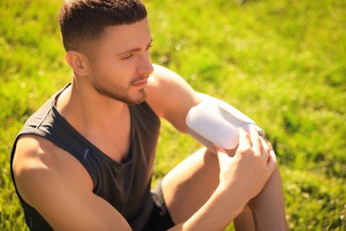 Photo of Attractive man checking blood pressure with modern monitor after training on sunny day