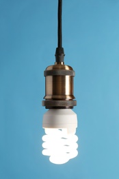 Photo of Hanging fluorescent lamp bulb against blue background