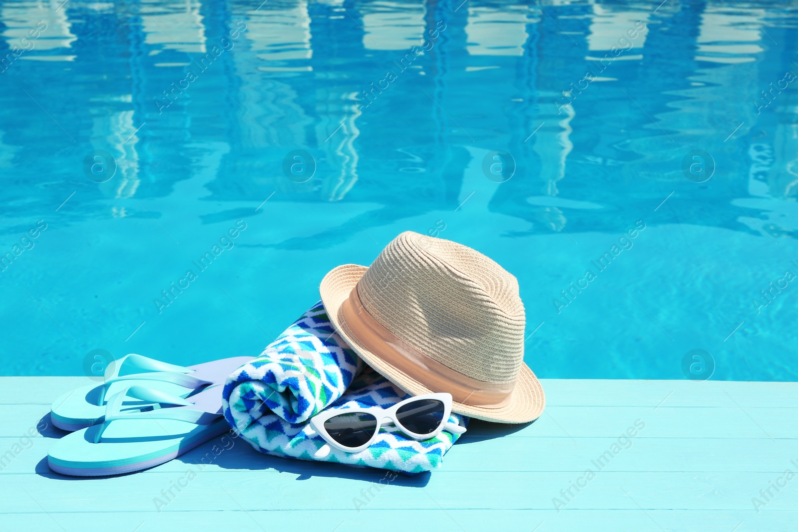 Photo of Beach accessories on wooden deck near swimming pool. Space for text