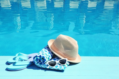 Photo of Beach accessories on wooden deck near swimming pool. Space for text