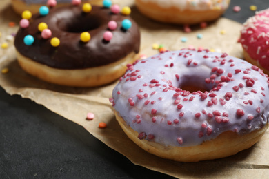 Photo of Yummy donuts with sprinkles on dark background, closeup