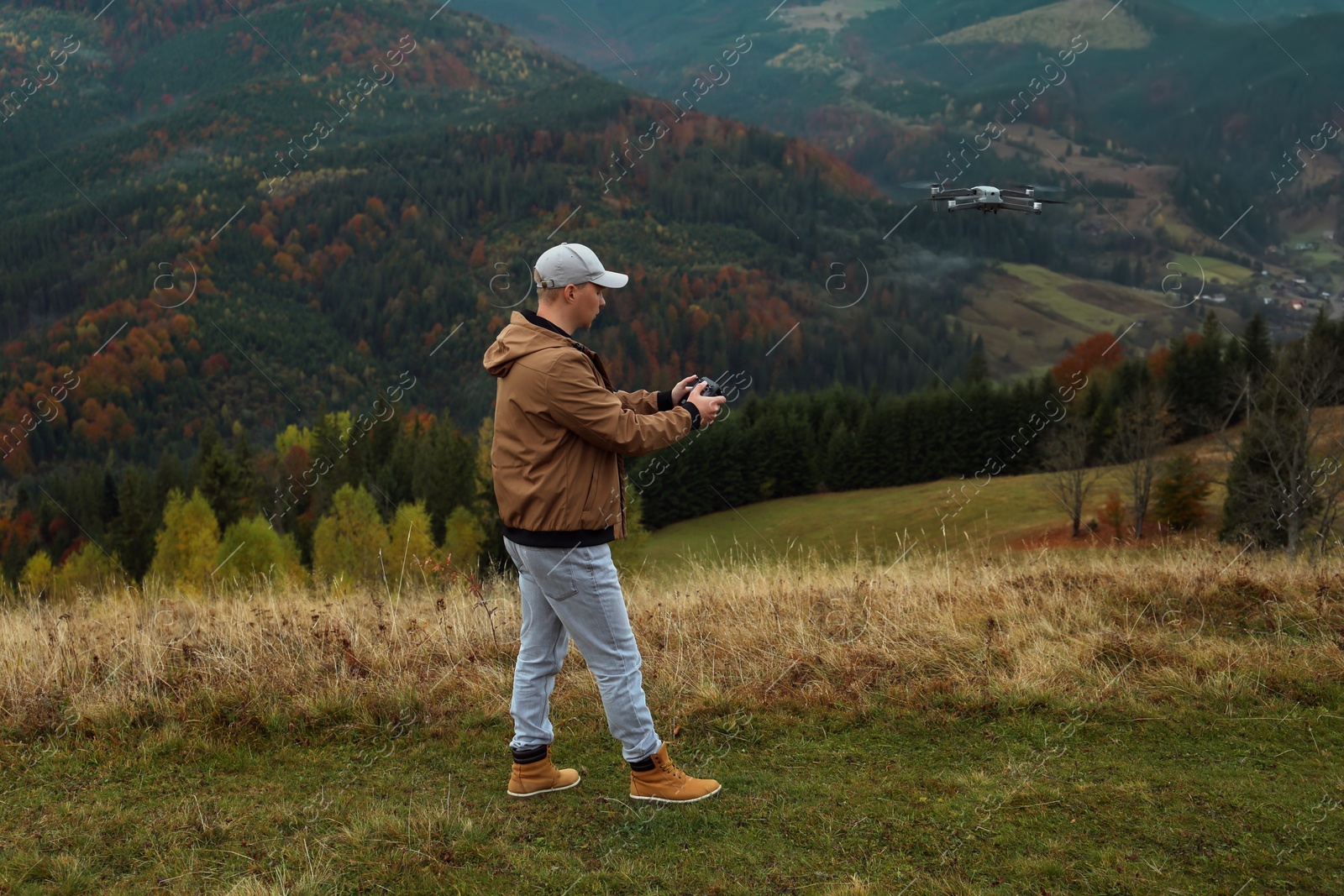 Photo of Young man operating drone with remote control in mountains