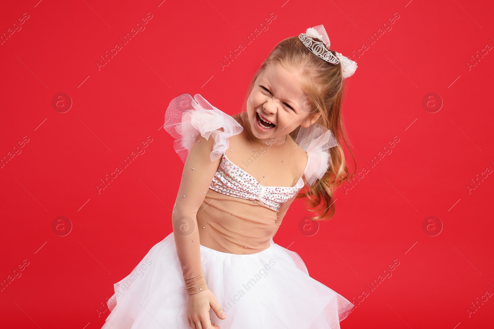 Photo of Cute girl in fairy dress with diadem on red background. Little princess