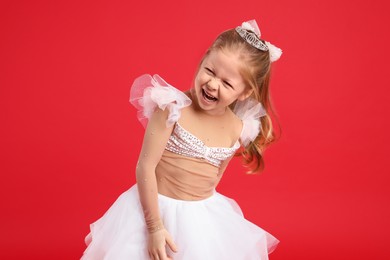 Cute girl in fairy dress with diadem on red background. Little princess