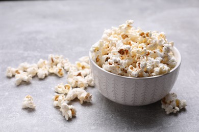 Photo of Bowl of tasty popcorn on grey table, space for text