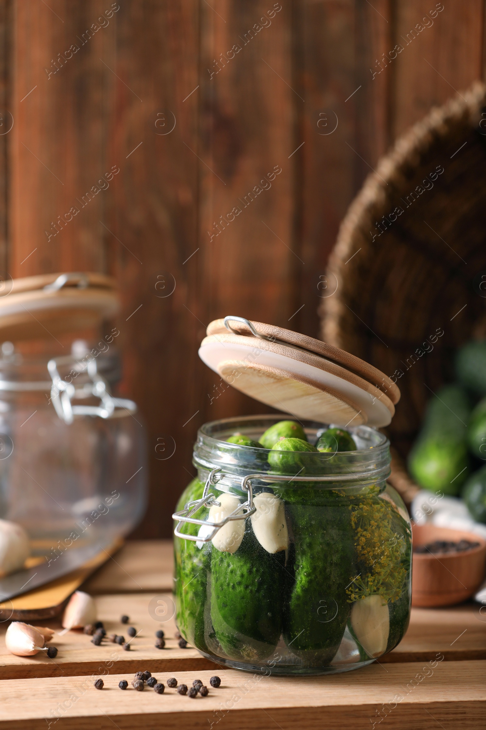 Photo of Glass jar with fresh cucumbers and other ingredients on wooden table. Canning vegetable