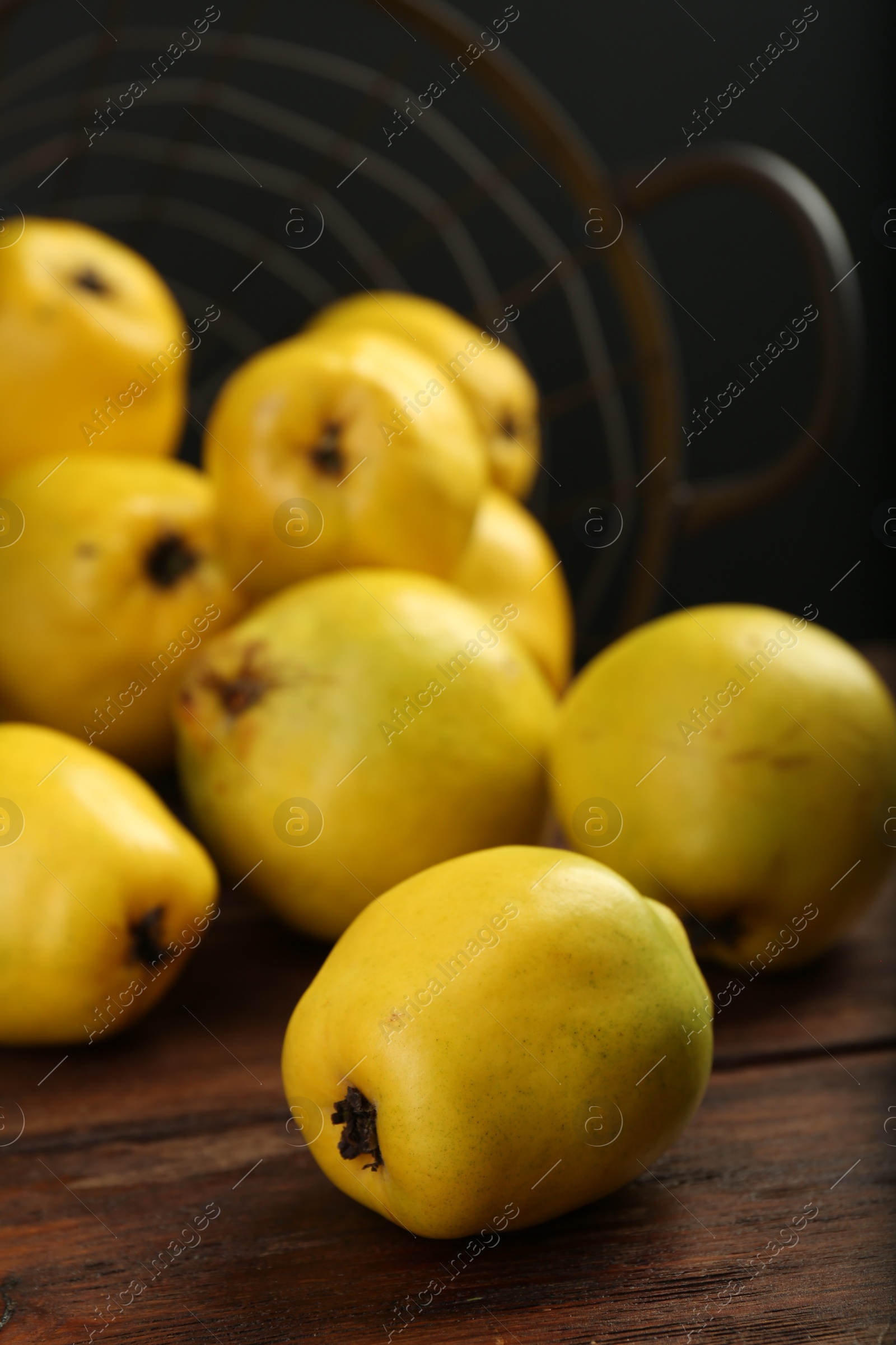 Photo of Delicious ripe quinces on wooden table against black background