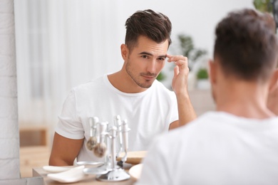 Photo of Young man with stubble ready for shaving near mirror in bathroom