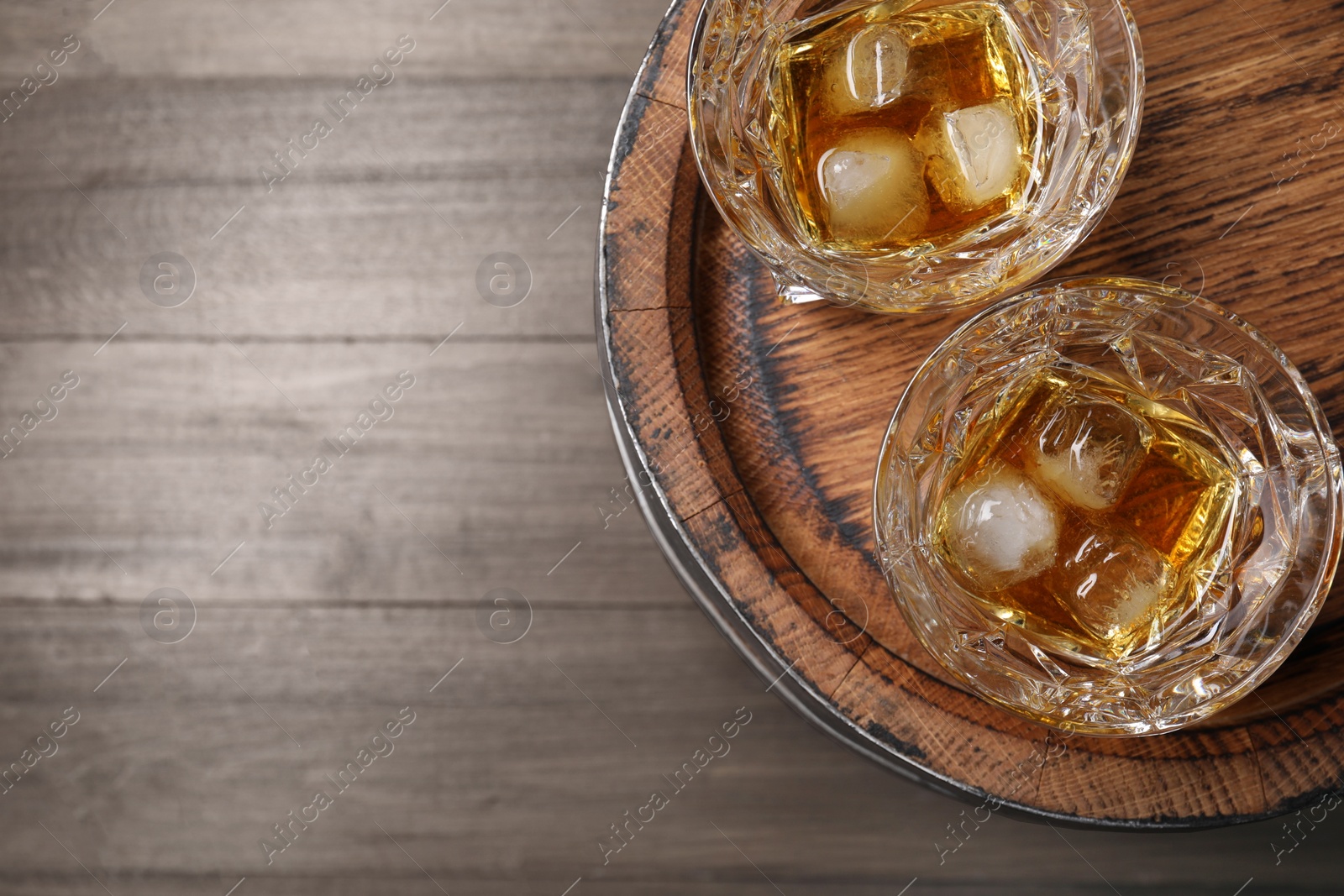 Photo of Barrel and glasses of tasty whiskey on wooden table, top view. Space for text