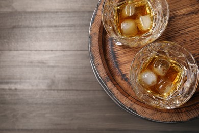 Photo of Barrel and glasses of tasty whiskey on wooden table, top view. Space for text