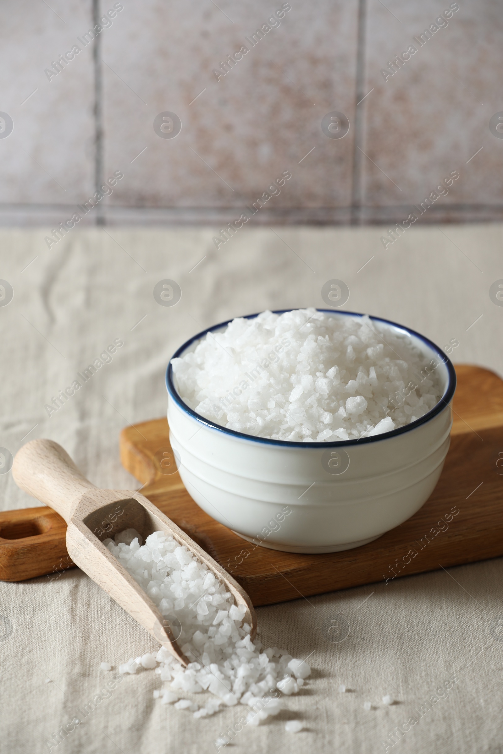 Photo of Organic salt in bowl and scoop on table