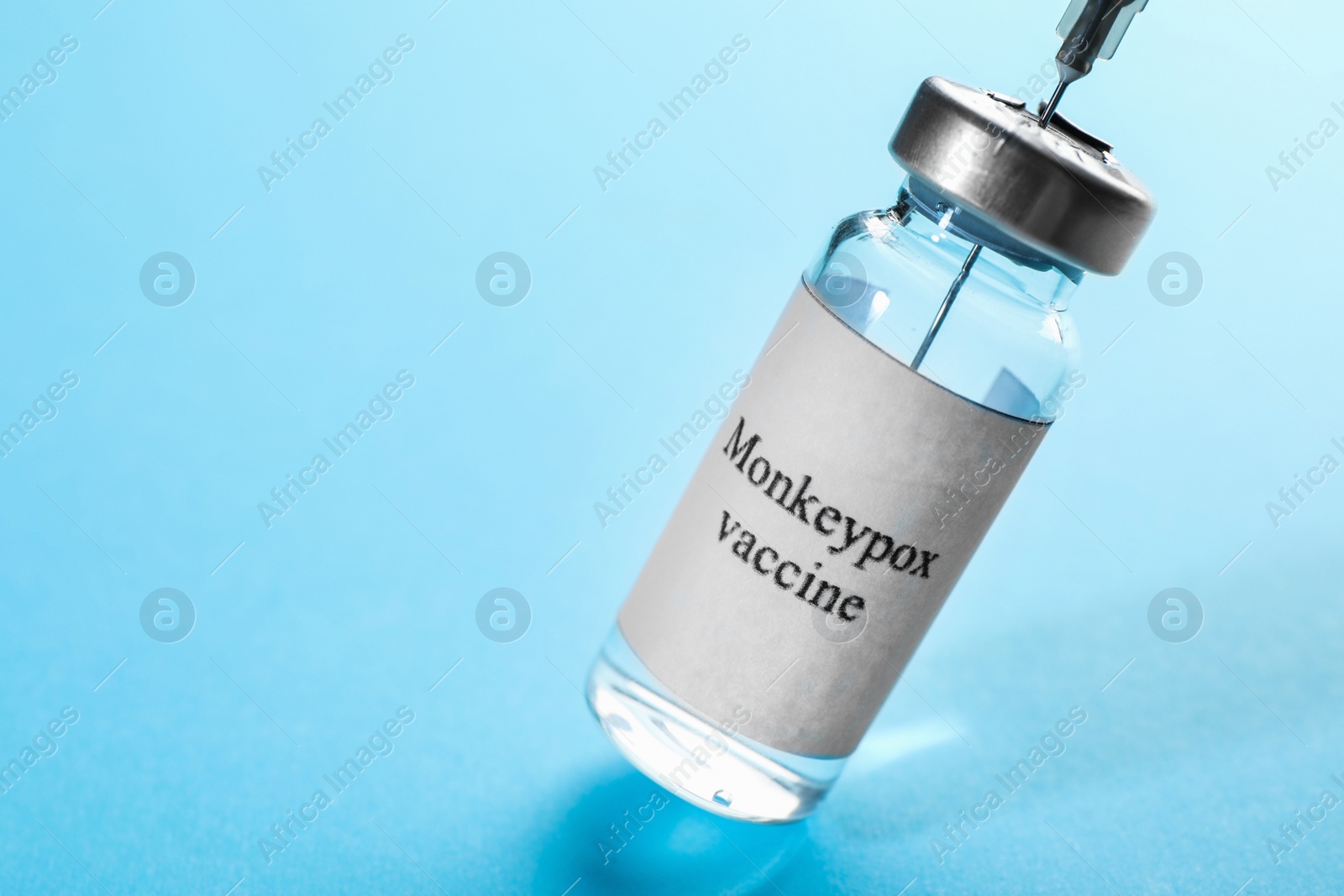 Photo of Filling syringe with monkeypox vaccine from vial on light blue background, space for text