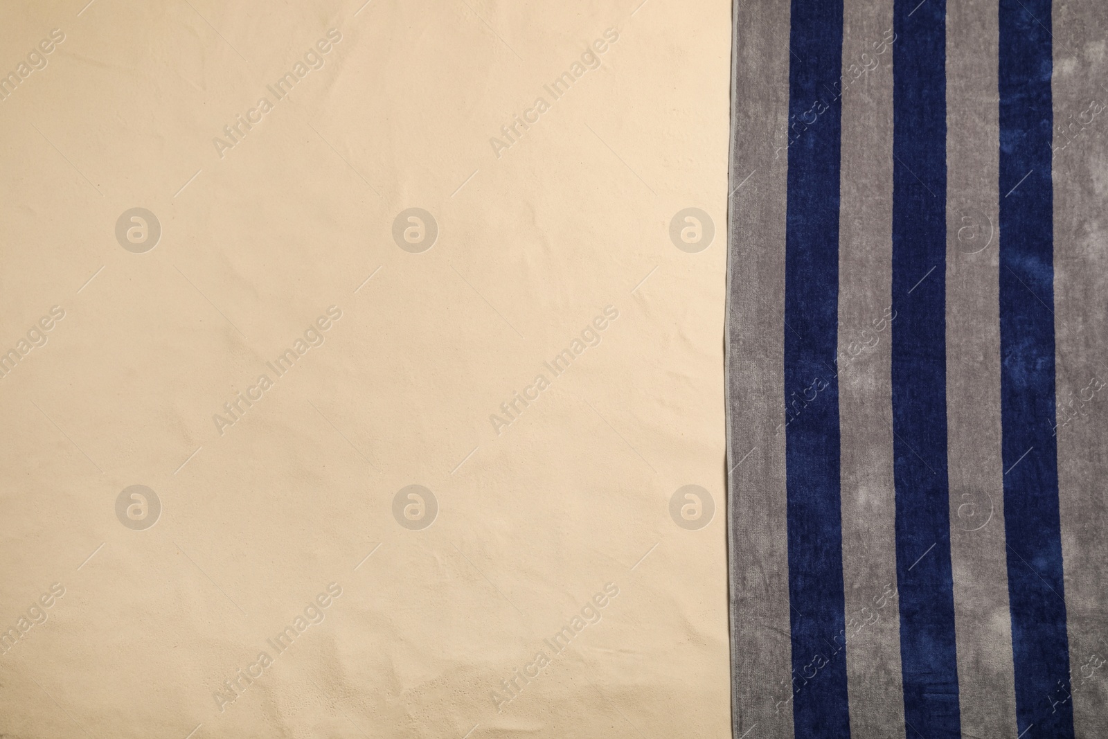 Photo of Striped beach towel on sand, top view. Space for text