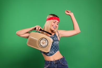 Happy hippie woman with retro radio receiver dancing on green background