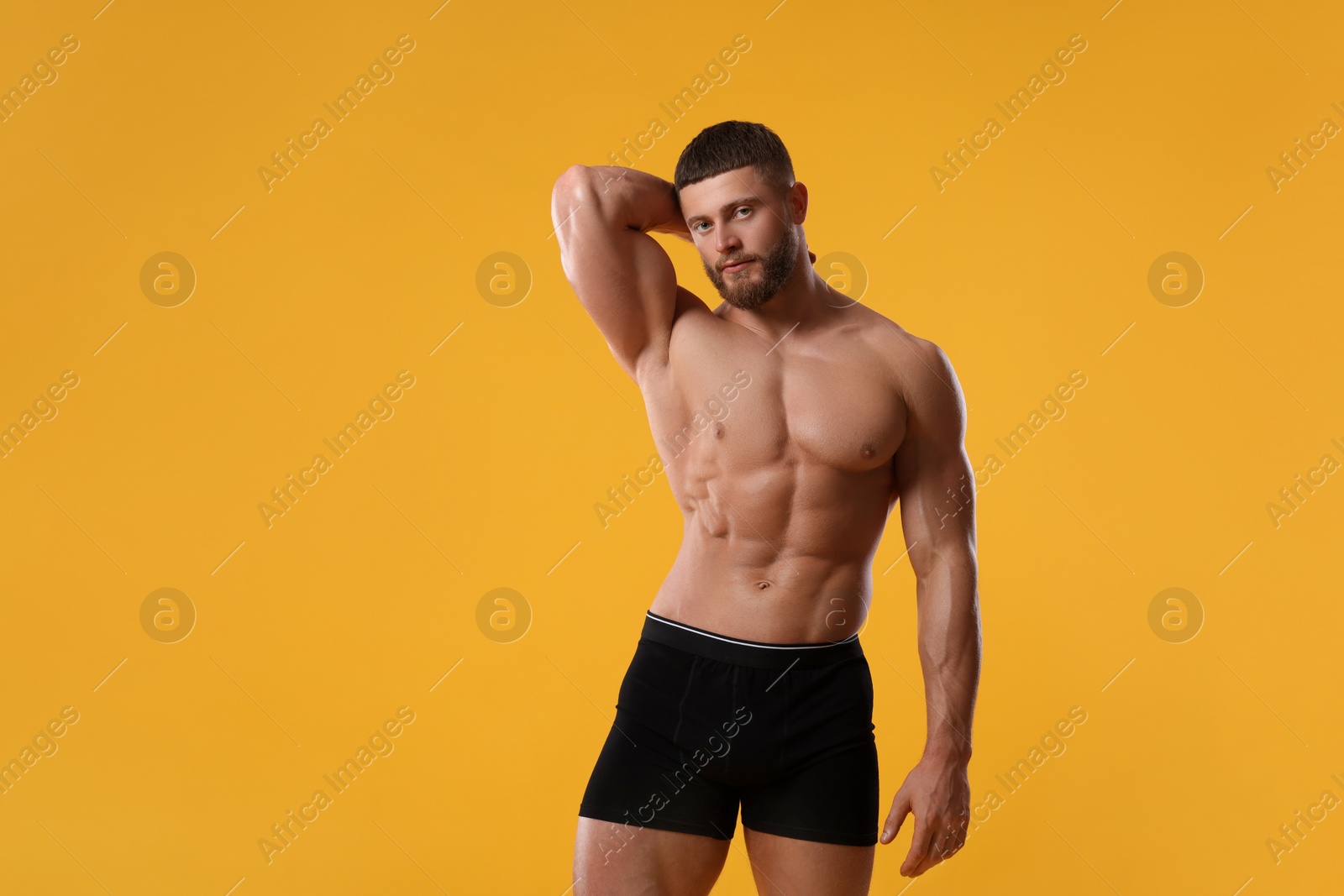 Photo of Young man is stylish black underwear on orange background