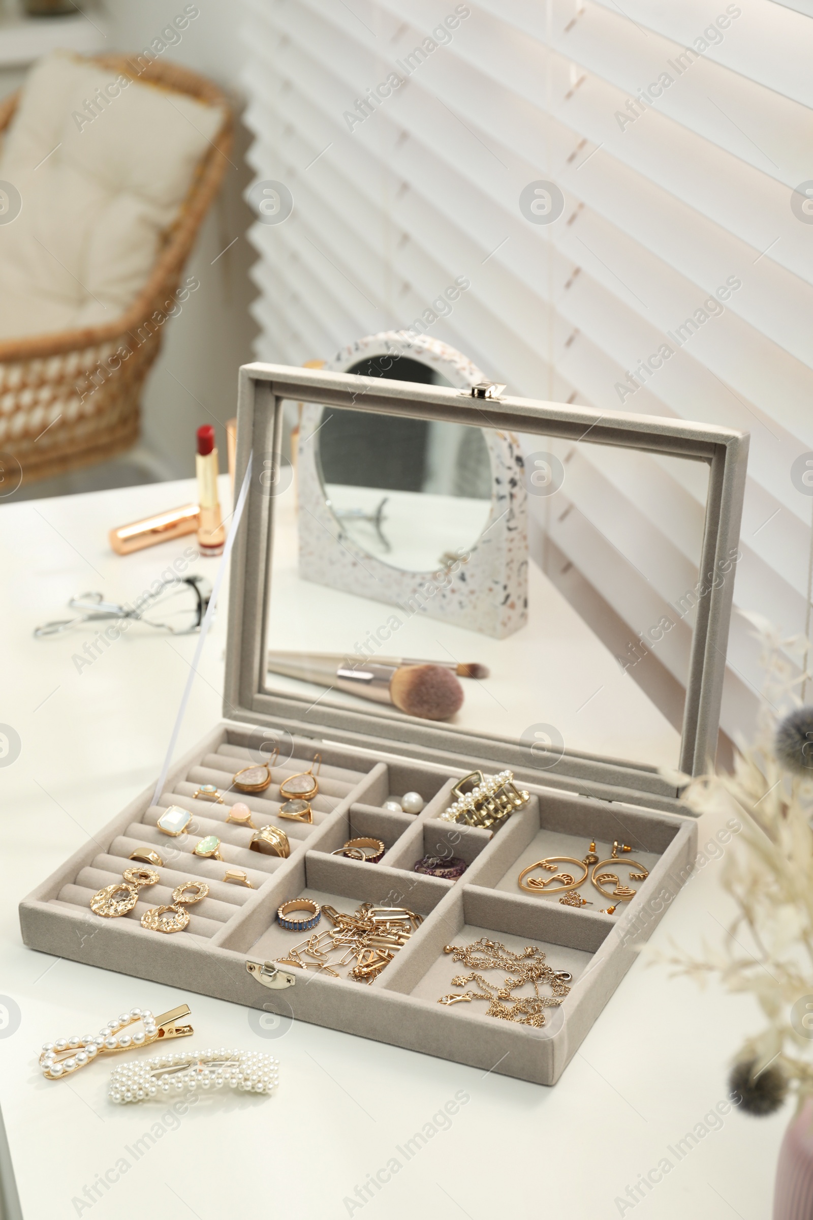 Photo of Elegant jewelry box with beautiful bijouterie and makeup products on dressing table indoors