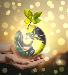 Woman holding Earth on light background, closeup